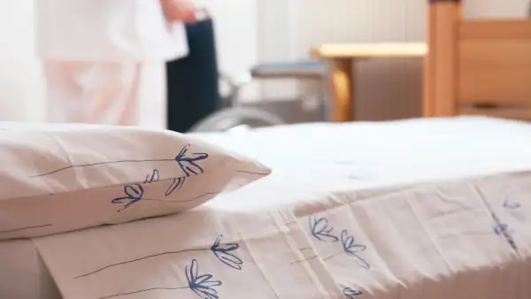 close up of a bed with clean white sheets with blue flower on them