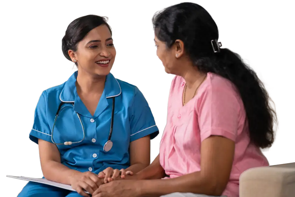 a younger caretaker sitting with an older woman holding her hand and smiling