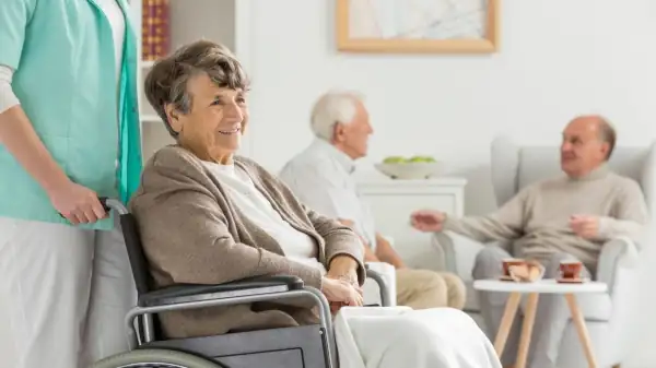 an older woman sitting in a wheel chair, being pushed by a caretaker